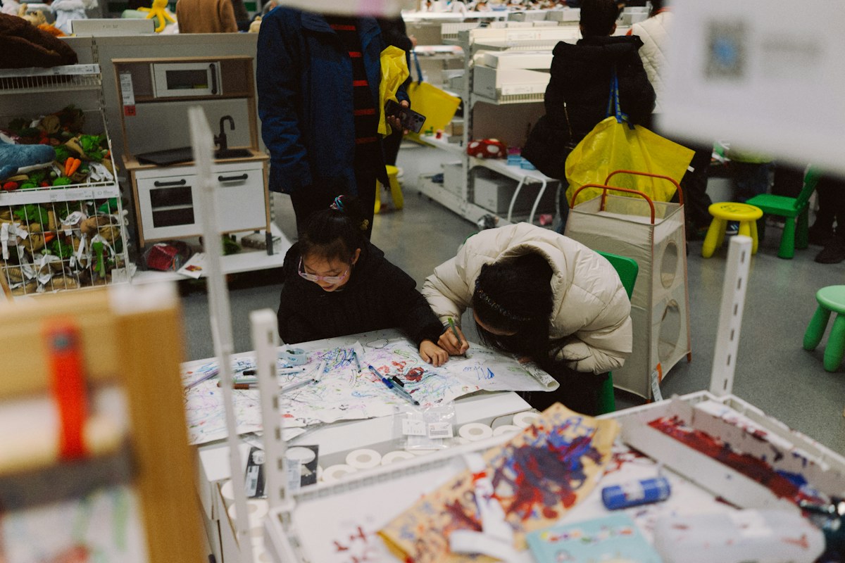 A child and another person draw together at a small table covered with colourful marks. Illustrative photo for this preview activity.
