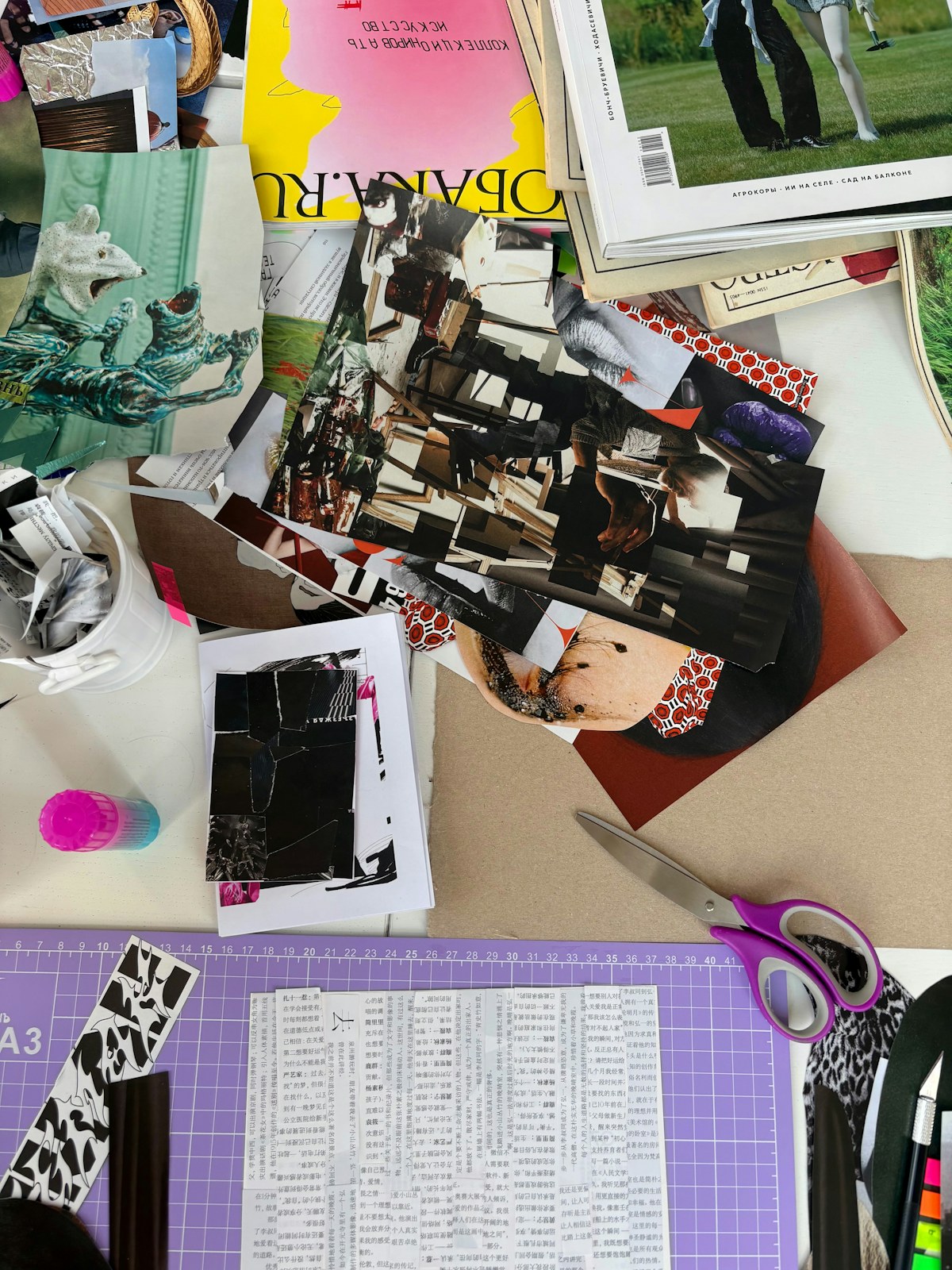 Paper cuttings, magazines, a glue stick and purple-handled scissors cover a craft table. Illustrative photo for this preview activity.