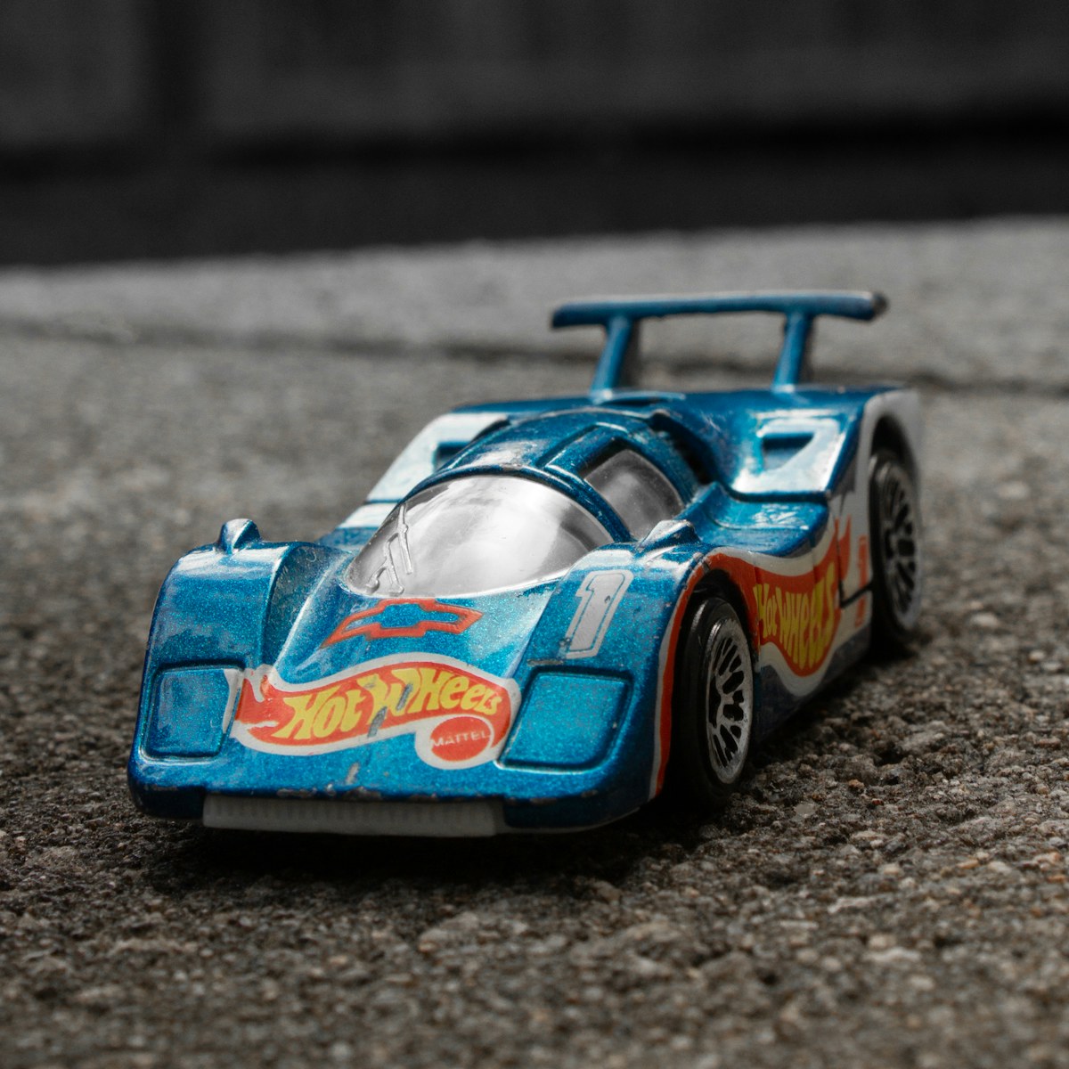 A blue toy racing car rests on a textured grey surface. Illustrative photo for this preview activity.