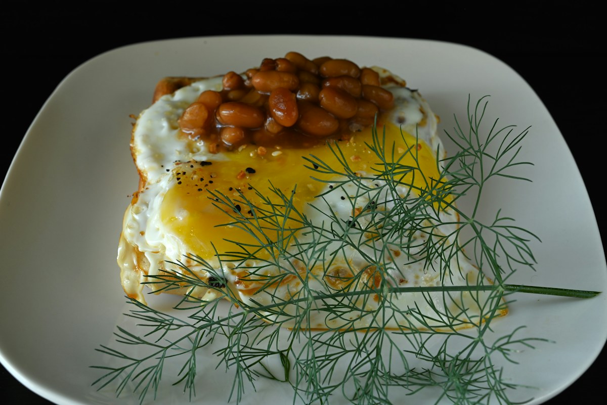 A baked potato topped with beans on a white plate. Illustrative food photograph; the finished recipe may look different.