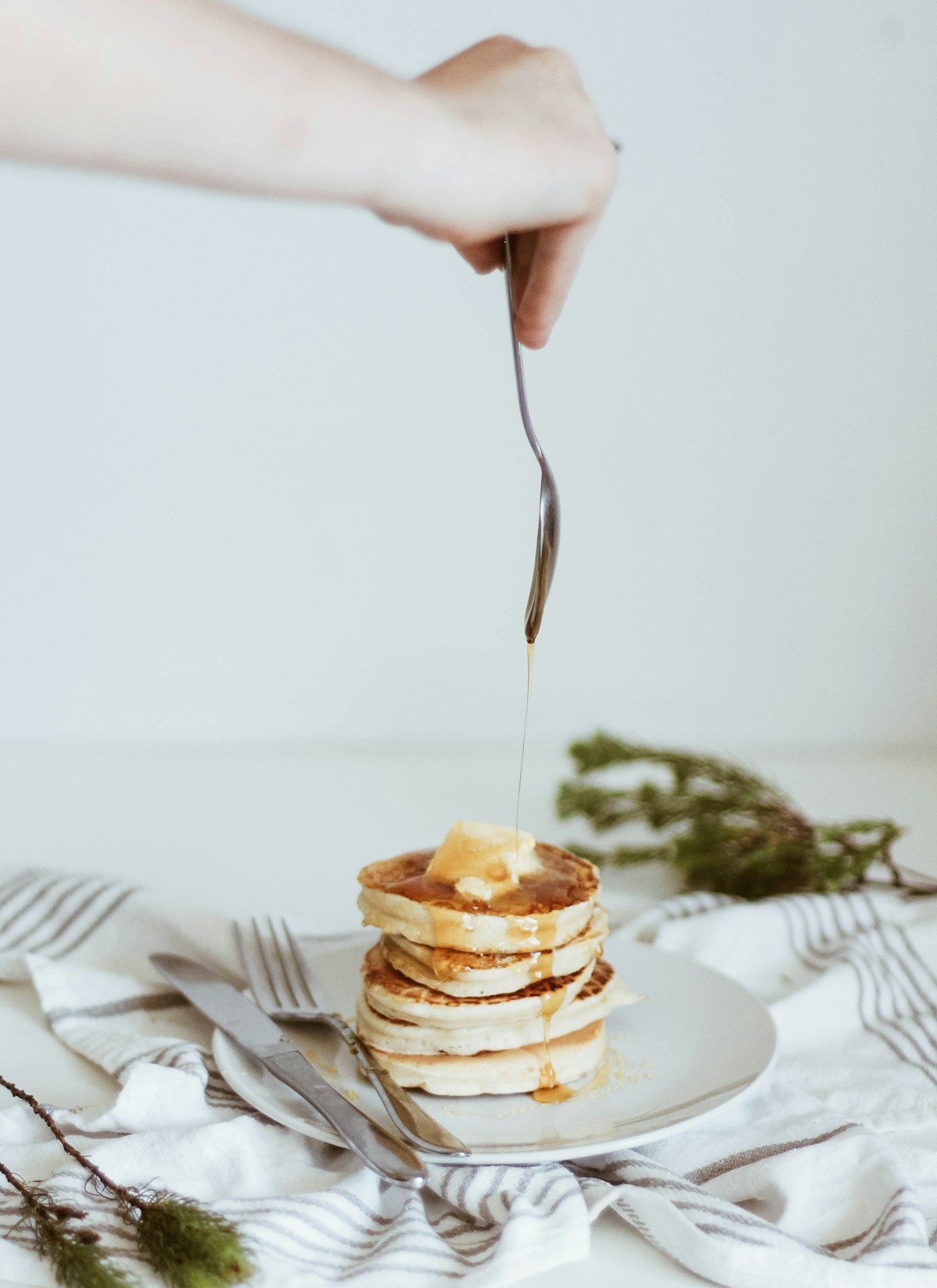 Honey being poured over a stack of pancakes on a white plate. Illustrative photograph for an original fictional story.