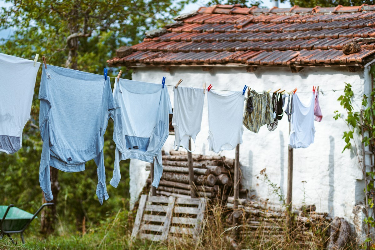 Pale laundry pegged to a washing line in a garden courtyard. Illustrative photograph for an original fictional story.