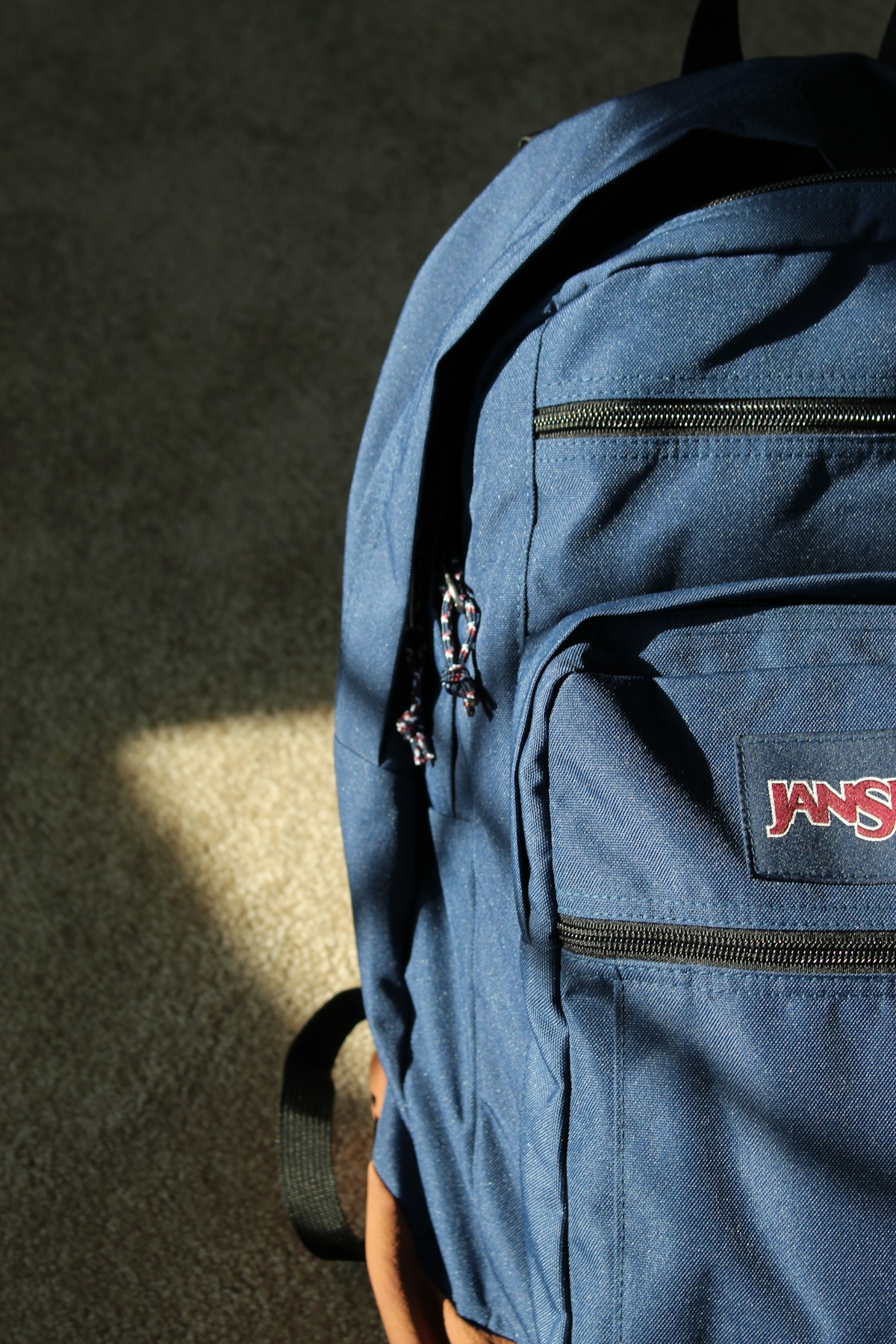 A blue backpack resting in a patch of sunlight on the floor. Illustrative photograph for an original fictional story.