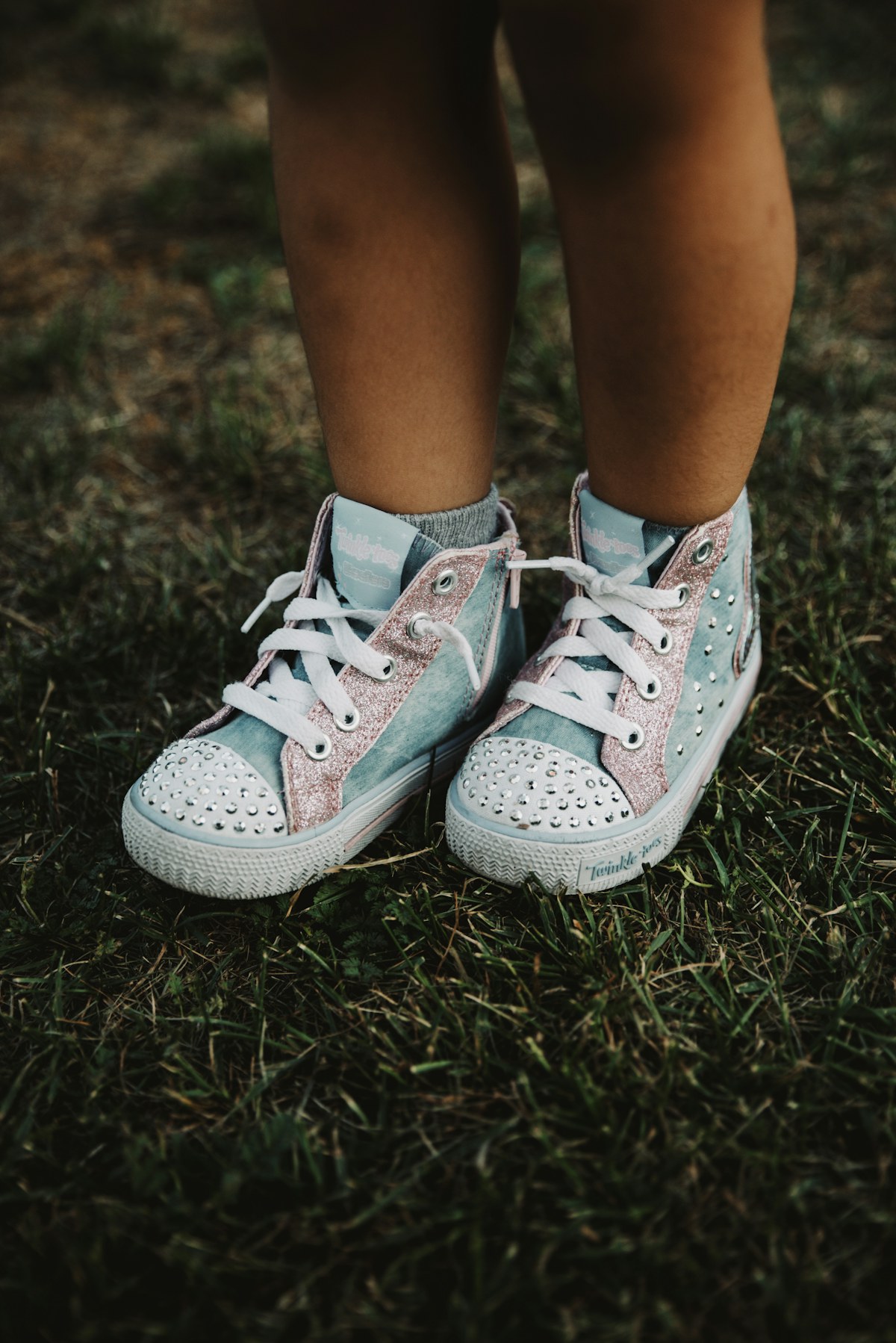 Blue and pink glitter trainers worn on green grass. Illustrative photograph for an original fictional story.